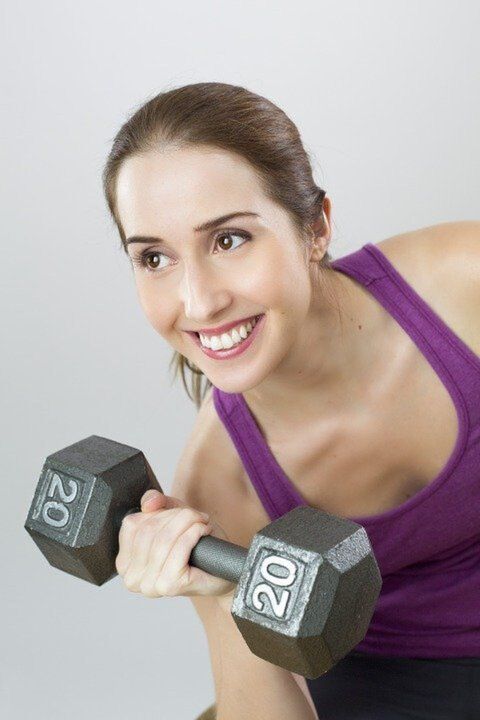 girl with a dumbbell performs a weight loss exercise